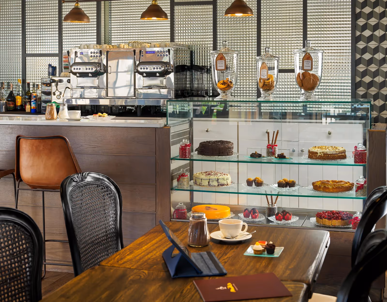 Caféhoek met een vitrine vol taarten en gebak, koffiemachines en een kopje koffie bij H10 Conquistador in Playa de las Américas