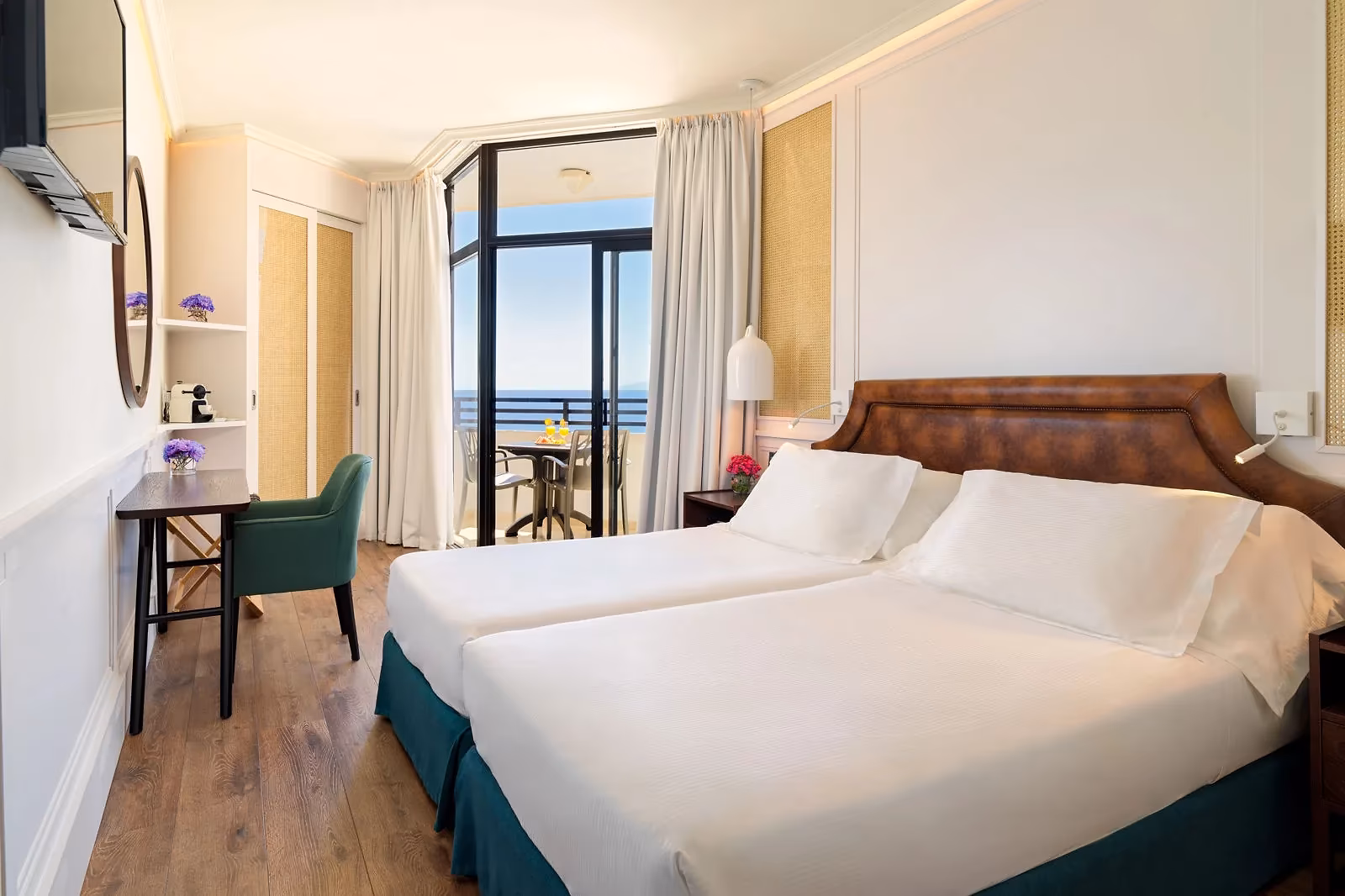 Tweepersoonskamer met een bruin hoofdbord, een groene stoel en een balkon met zeezicht bij H10 Conquistador in Playa de las Américas