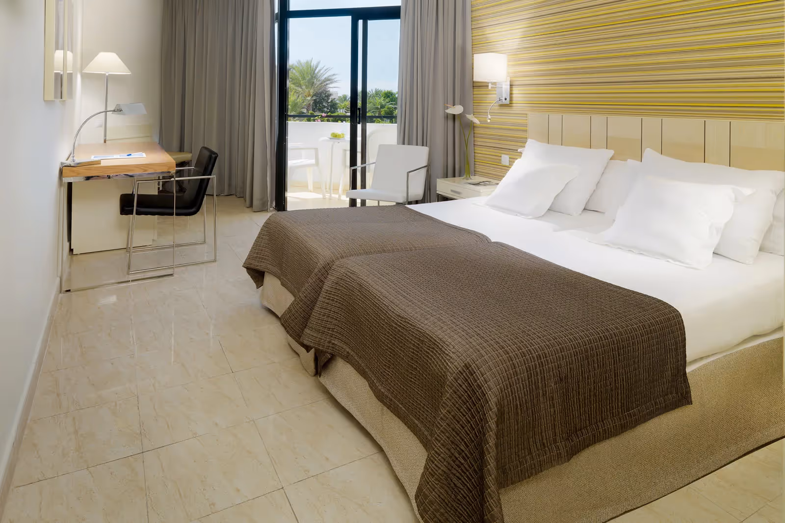 Kamer met twee bedden, een bruine sprei, een houten hoofdbord en een bureau bij het raam bij H10 Conquistador in Playa de las Américas