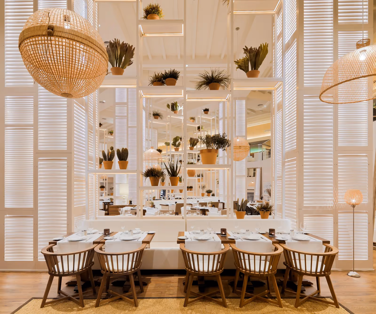 Restaurant met witte lamellenwanden, planten in terracotta potten, rieten hanglampen en een lange gedekte tafel bij H10 Conquistador in Playa de las Américas