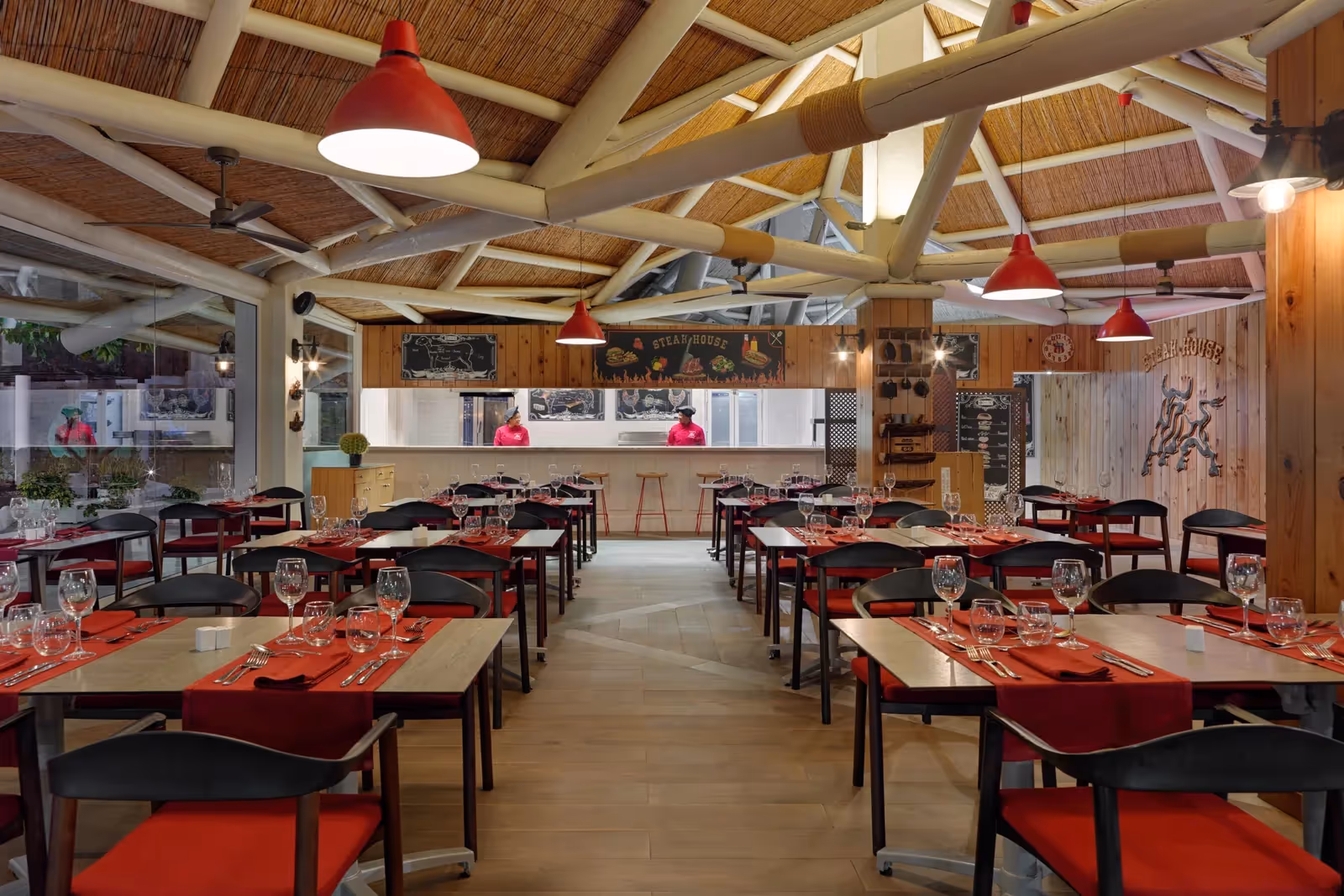 Steak House met rode stoelen en servetten, een houten dak, een open keuken en een stierlogo bij H10 Conquistador in Playa de las Américas