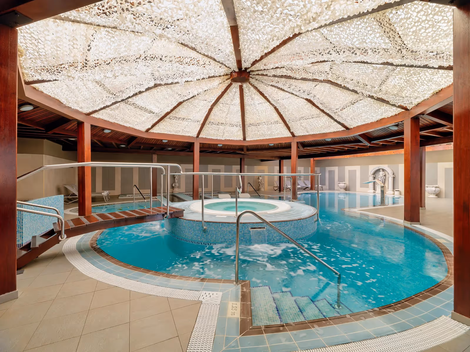 Zeewaterbad met jets en een ronde jacuzzi onder een koepeldak van witte netten, met een houten loopbrug bij H10 Conquistador in Playa de las Américas