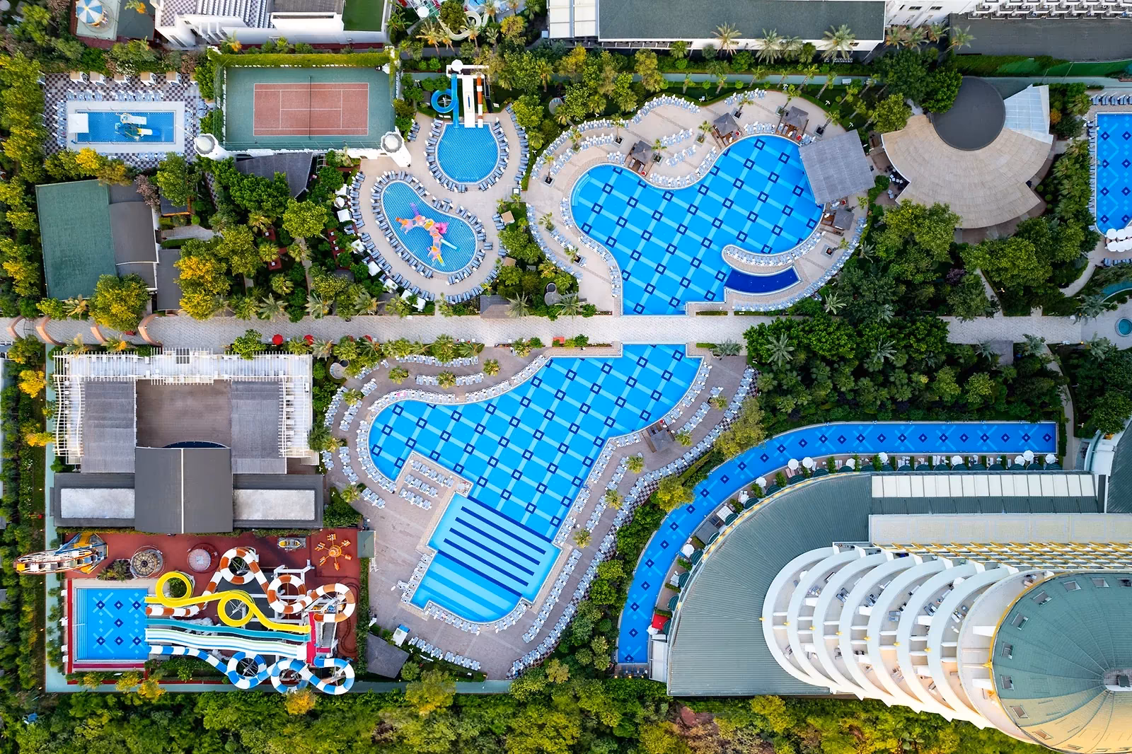 Delphin Imperial uit de lucht: het gebogen hoofdgebouw met baden en een glijbaanbad
