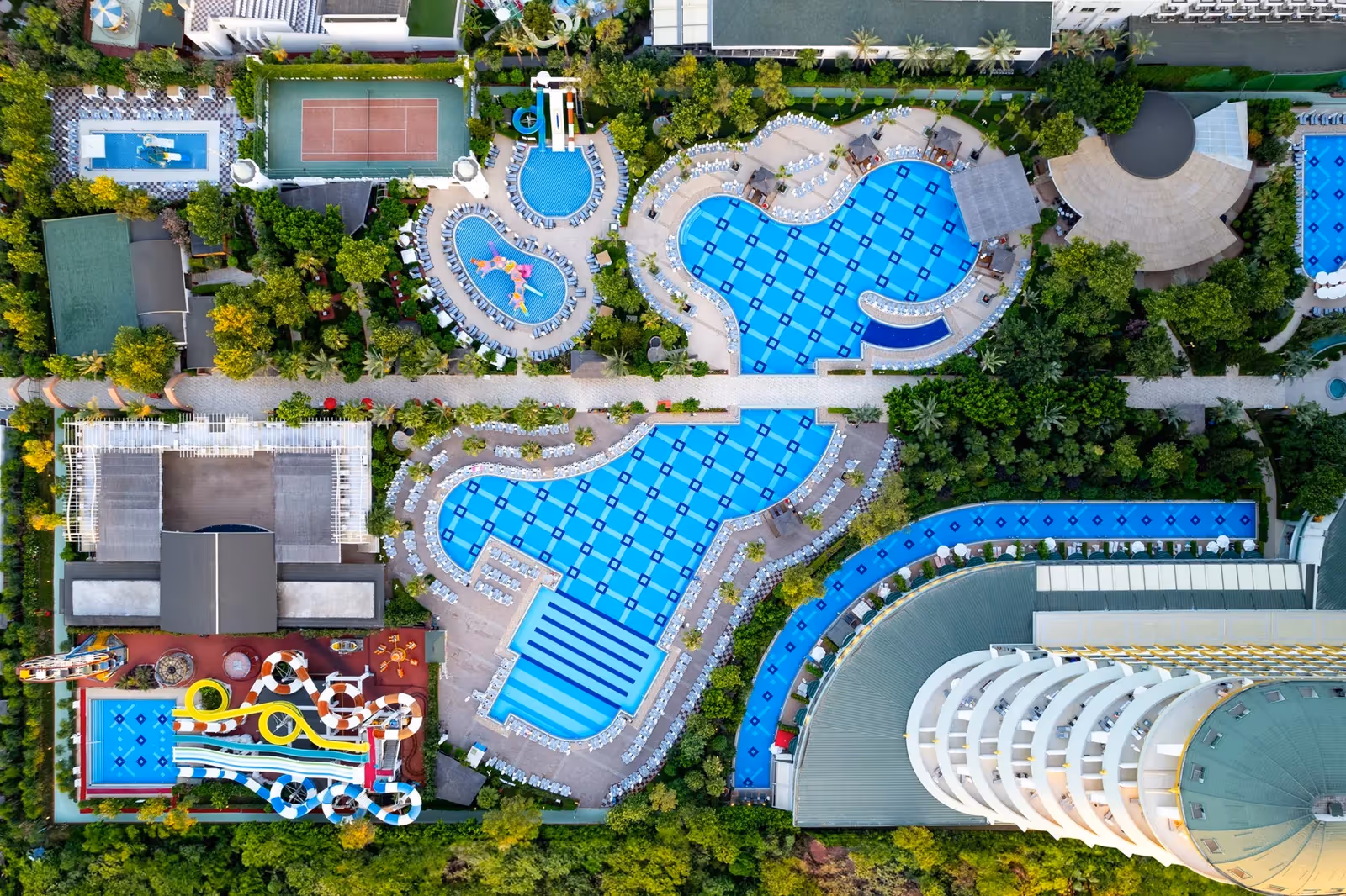 Delphin Imperial uit de lucht: het gebogen hoofdgebouw met baden en een glijbaanbad