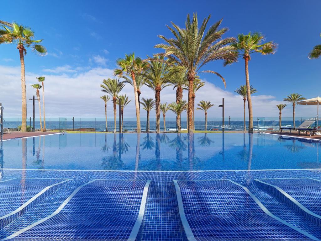 H10 Conquistador Resort zwembad ligstoelen met uitzicht over de oceaan met een heerlijke zon